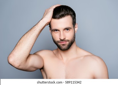 Young Handsome Naked Man Isolated On Gray Background Touching His Perfect Hair And Looking At Camera.