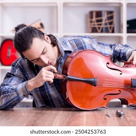 Young handsome repairman repairing cello - Powered by Shutterstock