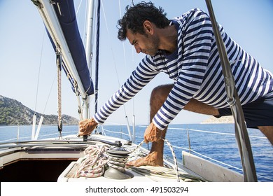 Young handsome sailor pulling rope on sailboat