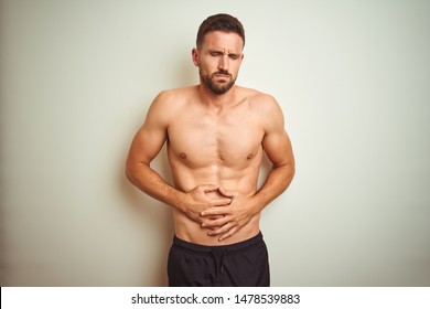 Young handsome shirtless man over isolated background with hand on stomach because nausea, painful disease feeling unwell. Ache concept.