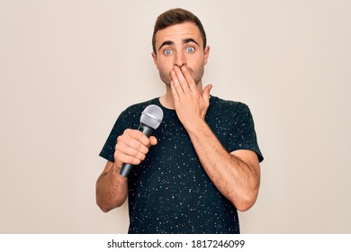 Young Handsome Singer Man With Blue Eyes Singing Using Microphone Over White Background Cover Mouth With Hand Shocked With Shame For Mistake, Expression Of Fear, Scared In Silence, Secret Concept