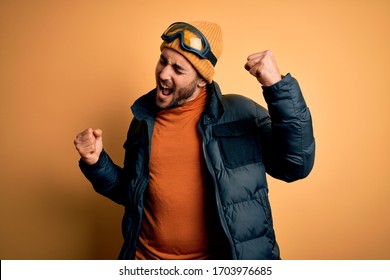 Young handsome skier man with beard wearing snow sportswear and ski goggles Dancing happy and cheerful, smiling moving casual and confident listening to music