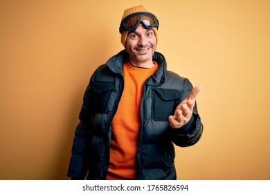 Young Handsome Skier Man Skiing Wearing Snow Sportswear Using Ski Goggles Smiling Friendly Offering Handshake As Greeting And Welcoming. Successful Business.