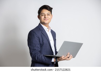 Young handsome smiling Indian teenager boy wearing suit holding laptop at isolated on white studio background. Asian corporate male using computer. cloud computing  - Powered by Shutterstock