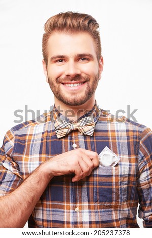 Young Handsome Smiling Man Putting A Condom Into His Shirt Pocket Isolated On White Background Young Handsome Smiling Man Putting A Condom Into His Shirt Pocket Isolated On White Background