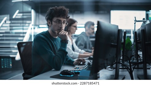 Young Handsome Software Developer Working on Computer in a Technological Laboratory Environment. IT Programming Department Tirelessly Researching and Developing Advanced Commercial Internet Products - Powered by Shutterstock