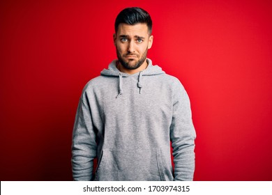 Young Handsome Sportsman Wearing Sweatshirt Standing Over Isolated Red Background Depressed And Worry For Distress, Crying Angry And Afraid. Sad Expression.