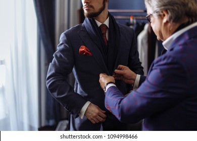 Young, handsome and successful businessman trying on a custom made stylish suit at tailors shop. Dressmaking and Tailoring establishment concept
