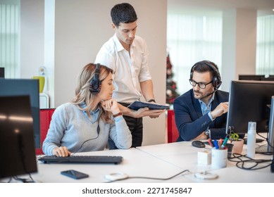 Young handsome supervisor bringing and showing performance review to his employees at call center. - Powered by Shutterstock