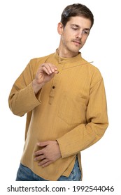 Young Handsome Tall Slim White Man With Brown Hair Looking At Incense Stick In Ochre Shirt Isolated On White Background