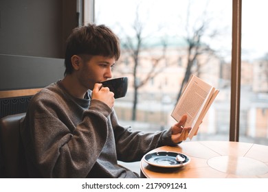 Young handsome teenage boy 18-19 year old drinking coffee sitting in cafe and reading paper book. Millennials lifestyle.  - Powered by Shutterstock