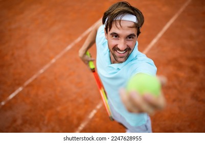 Young handsome tennis player with racket and ball prepares to serve at beginning of game or match. - Powered by Shutterstock