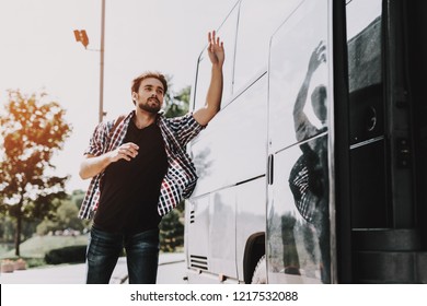 Young Handsome Tourist Almost Late For Bus. Man With Backpack Running After Tour Bus And Asking Bus Driver To Stop By Waving Hand. Traveling, Tourism And People Concept. Active Lifestyle