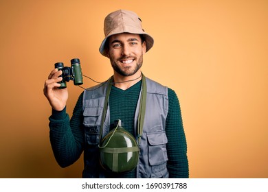 Young handsome tourist man with beard on vacation wearing explorer hat using binoculars with a happy face standing and smiling with a confident smile showing teeth - Powered by Shutterstock