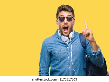 Young handsome tourist man wearing headphones and backpack over isolated background pointing finger up with successful idea. Exited and happy. Number one. - Shutterstock ID 1173517663