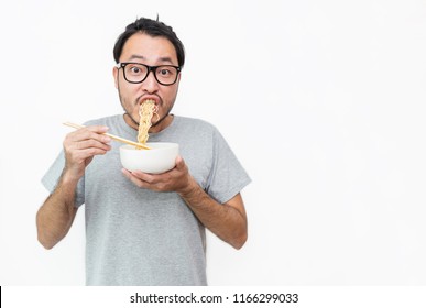 Young Handsome Trendy Asian Nerd Man Eating Yummy Hot And Spicy Instant Noodle Using Chopsticks Isolated On White Background. Asian Guy Servile End Of The Month With Cooking Cheap Unhealthy Food.