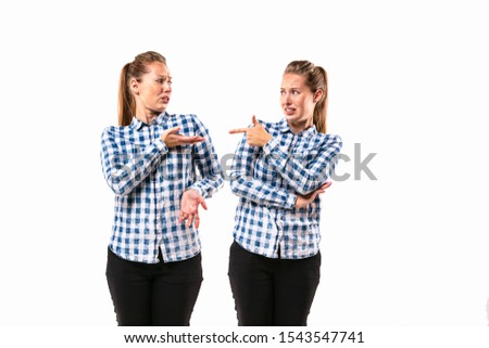 Young handsome woman arguing with herself on white studio background. Concept of human emotions, expression, mental issues, internal conflict, split personality. Half-length portrait. Negative space.