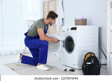 Young Handyman Fixing Washing Machine At Home. Laundry Day