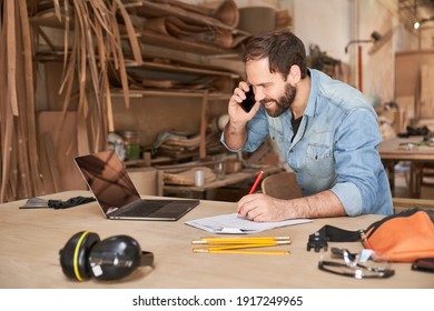 Young Handyman Man Using Laptop Computer While Talking To Customer On The Phone