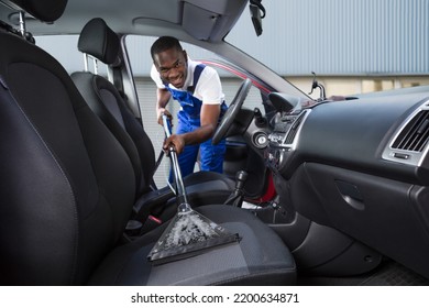 Young Handyman Vacuuming Car Front Seat With Vacuum Cleaner