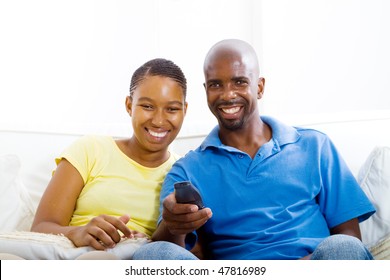 young happy african american couple watching TV on sofa