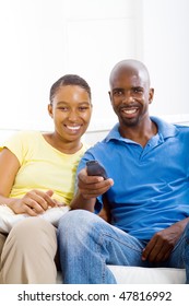young happy african american couple watching TV on sofa