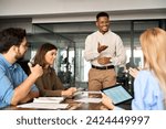 Young happy African American male executive company leader discussing project management planning strategy working with diverse busy colleagues company team at office corporate board group meeting.