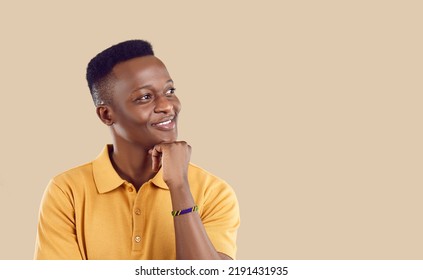 Young happy African American man student looks away with smile remembers home and loved ones props head up with hand dreams of happy future and career stands on beige studio background - Shutterstock ID 2191431935