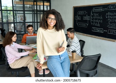 Young happy African American woman team leader sitting on desk holding tablet and international business startup students working studying at desk on project in contemporary classroom office. Portrait - Powered by Shutterstock