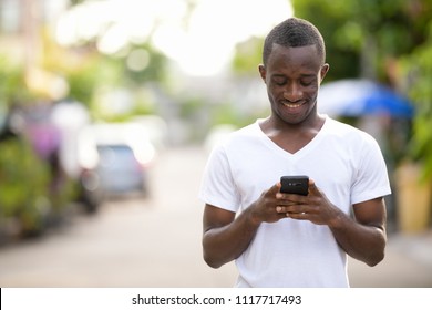 Young Happy African Man Smiling While Using Phone In The Streets Outdoors