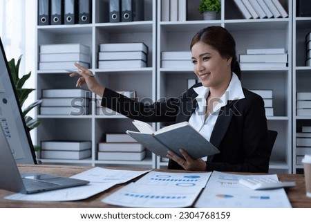 Young happy Asian businesswoman point on board for explain discuss example the figure loan rates interest target, Businesswoman holding book and point on white board