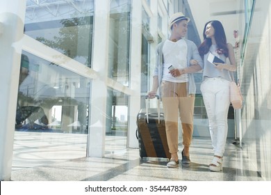 Young Happy Asian Couple With Luggage Walking In The Airport