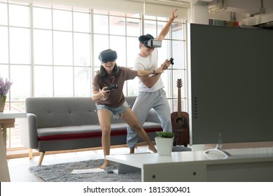 Young happy Asian couple playing video games wearing virtual reality glasses in their apartment - Powered by Shutterstock