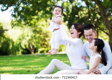 Young Happy Asian Family Spending Time Together At The Park.