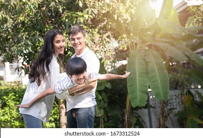 Young happy asian father,mother and son playing in the park at the day time at front house yard. Concept of friendly family.