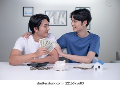 Young Happy Asian Gay Couple Saving Money To Buy A House. LGBT Men Couple Saving Money For Family And Home.