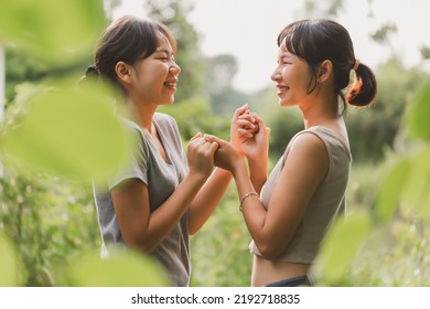 Young happy Asian girls standing holding hands with smiley face in green nature background. Two teenager women spend time together with happy moment. Lesbian LGBTQ couple concept. - Powered by Shutterstock