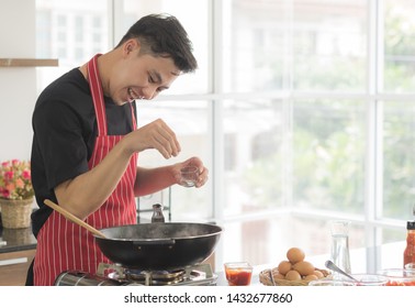 Young Happy Asian Man Cooking Ingredient In Pan To Make Delicious Food, Pour Salt