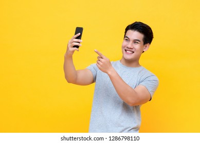 Young Happy Asian Man Selfie With Smartphone In Colorful Yellow Background