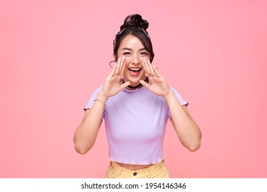 Young happy asian teen woman shout story or making announcement isolated on pink background.