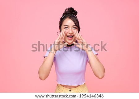 Young happy asian teen woman shout story or making announcement isolated on pink background.