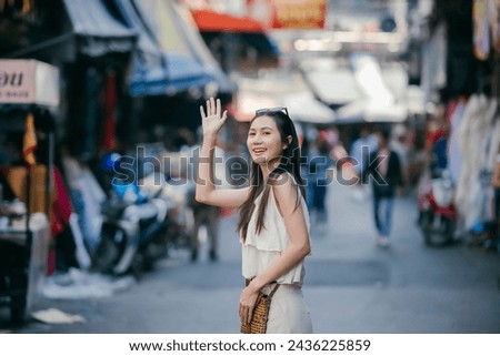 Young happy Asian treveler greeting local people on the locol market.