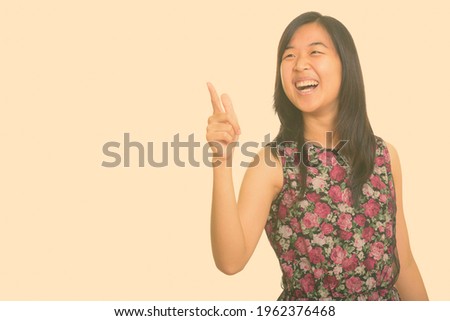 Young happy Asian woman laughing while pointing finger