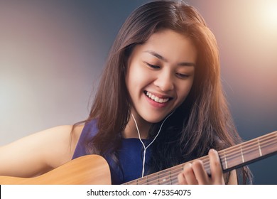 Young Happy Asian Woman Listening Music With Earpiece, Acoustic Guitar Player.