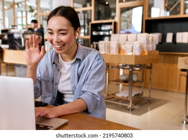 Young Happy Asian Woman Worker Or Student Using Laptop Computer Waving Hand, Talking, Having Hybrid Remote Video Call Virtual Meeting Or Online Distance Interview, Participating Webinar Training.
