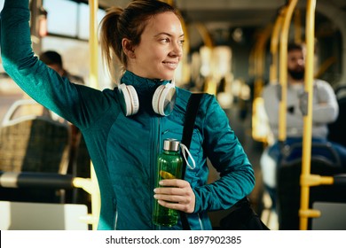 Young Happy Athletic Woman Carrying Water Bottle And Looking Away While Commuting By Bus.