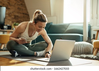 Young happy athletic woman surfing the net on laptop while taking a break from exercising at home.  - Shutterstock ID 1662427033