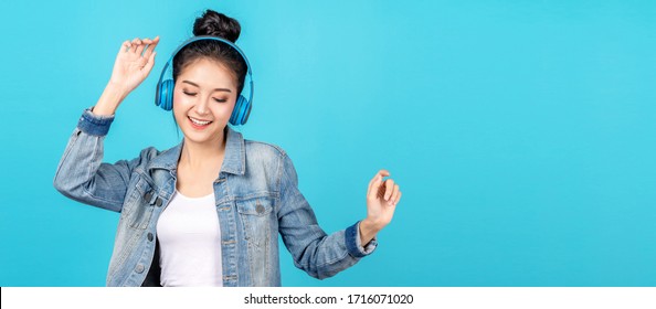 Young Happy Attractive Asian Woman Using Headphone Enjoy Listen To Song In Concept Of Next Normal Life, Pastime Or Hobby Online. Quarantine Activity Asian Lifestyle Listening To Music On Radio Online.