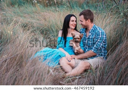 Young happy attractive couple posing with their dog - yorkshire terrier on nature,love,lifestyle,relationship 