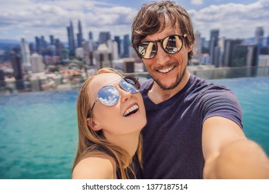 young happy and attractive playful couple taking selfie picture together at luxury urban hotel infinity pool and panoramic view of the city enjoying holidays honeymoon travel in diversity ethnicity - Powered by Shutterstock